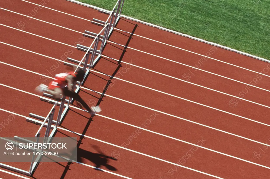 Track and field competition, hurdler on rust coloured track