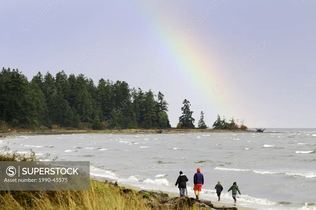 A family enjoys a walk along the beach in Parksville, British Columbia, Canada.