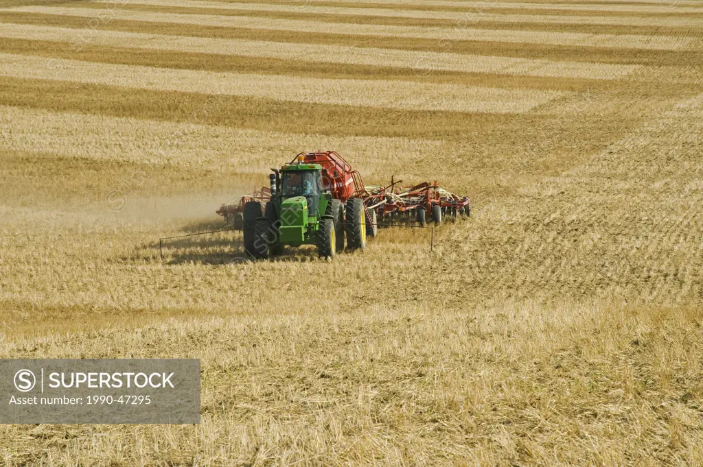 Moving tractor and air till seeder planting canola in a zero till wheat stubble field, Bruxelles, Manitoba, Canada