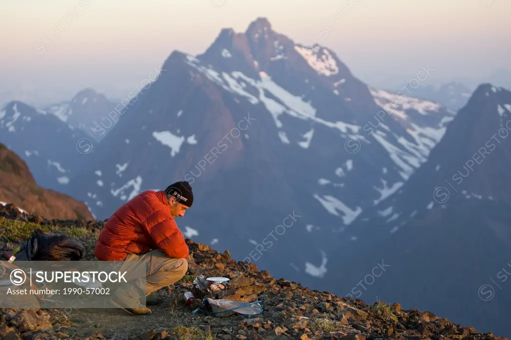 A lone climber prepares dinner while setting up camp on Elkhorn Mountain. Strathcona Park, Central Vancouver Island, British Columbia, Canada