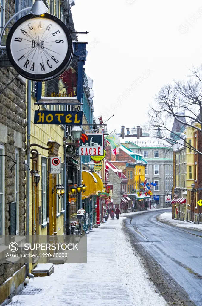 Tourists walking on an old street with Heritage commercial buildings in the Old Quebec in winter during a snowfall, Quebec, Canada