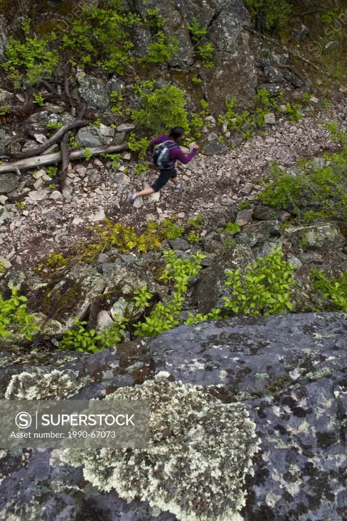 A young asian woman trail running in the 3 Blind Mice trail system. Penticton, BC