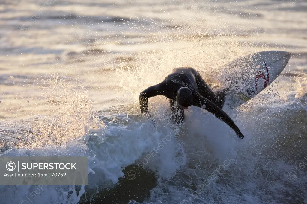 A surfer ripping through the crest of a wave in Rosie Bay, Tofino, Vancouver Island, British Columbia, Canada