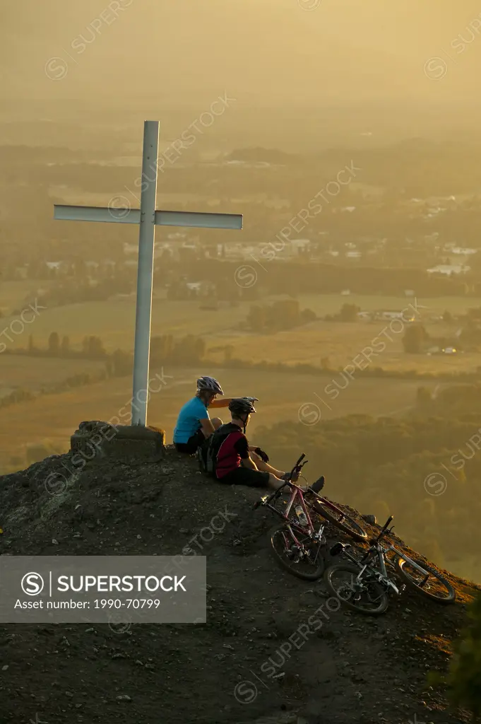 Friends rest along a mountain bike trail on Mt. Tzoulalem overlooking Duncan, Central Vancouver Island, British Columbia, Canada