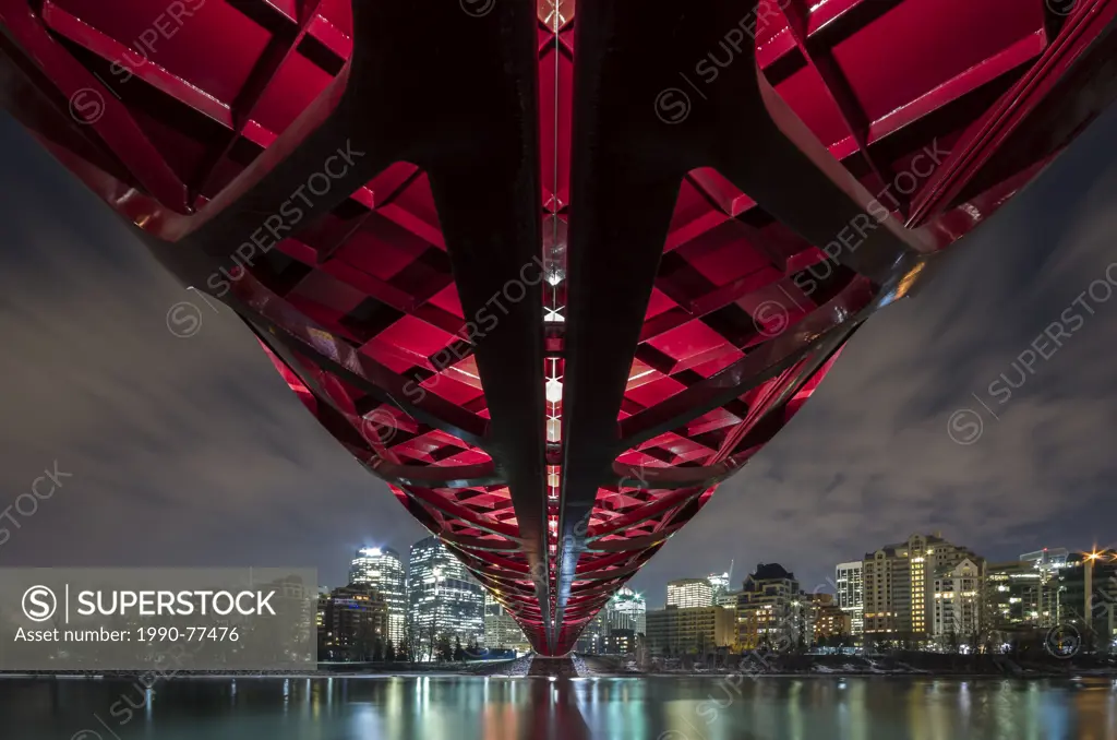 Pedestrian Peace Bridge and Downtown Calgary reflecting in the Bow River at night. Calgary, Alberta, Canada.