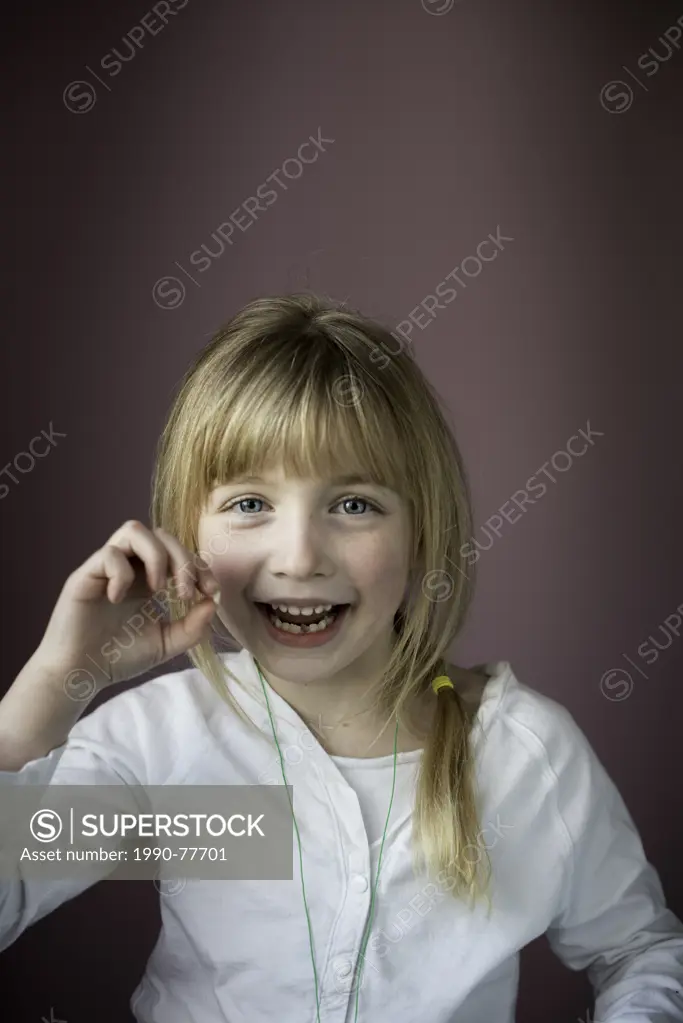 Smiling little girl showing her first loose tooth