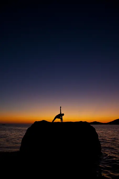 a young woman practicing yoga at sunset. Kalymnos, Greece
