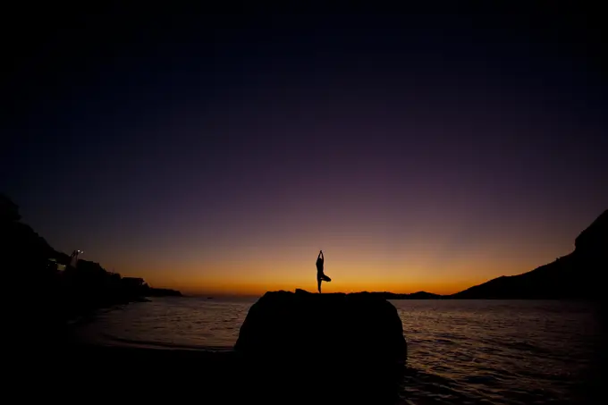 a young woman practicing yoga at sunset. Kalymnos, Greece