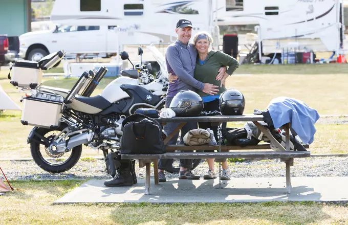 a happy mature couple packs up their campsite in preparation for a days ride on the North Island.