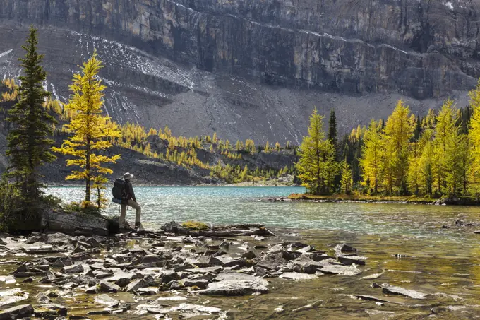 A back packer pauses on the shore of Skoki Lake in the Skoki wilderness area of Banff National Park, Alberta, Canada. Model Released