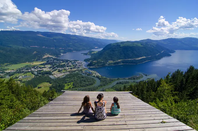 Woman and young girls enjoy an extraordinary summer viewscape from the glider ramp overlooking Sicamous, the Eagle River and Shuswap Lake in British C...