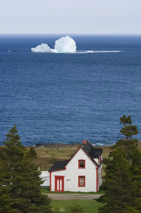 Coastal home and iceberg, Newfoundland, Canada