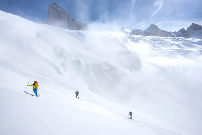 Three backcountry skiers climbing up onto the Conrad Icefield, a major ascent on the first day of the Bugaboos to Rogers Pass ski traverse, British Co...