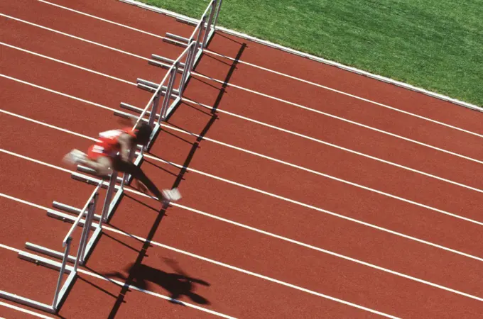 Track and field competition, hurdler on rust coloured track