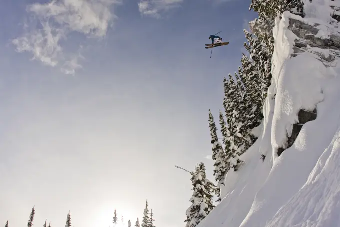 A male freeskier jumping a cliff at Sunshine Village, AB