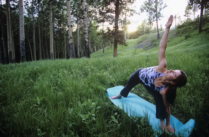 Woman doing yoga in meadow, Banff, Alberta, Canada.