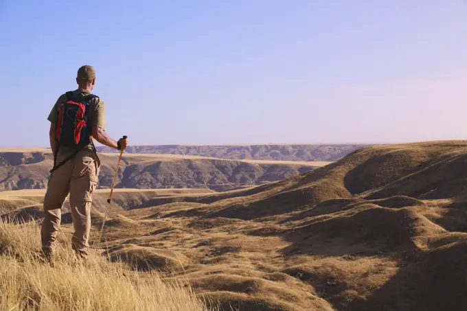 Hiker overlooking the coulees and badlands of the South Saskatchewan River this mixed grass prairie habitat is endangered in Alberta and Saskatchewan,...