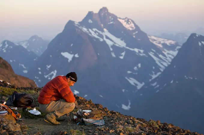 A lone climber prepares dinner while setting up camp on Elkhorn Mountain. Strathcona Park, Central Vancouver Island, British Columbia, Canada