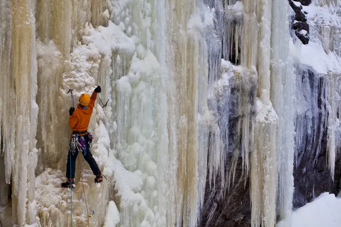 A man climbs a steep, colorful ice climb, Aurorae WI 4+, near St. Raymond, Quebec, Canada