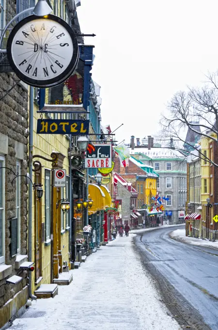 Tourists walking on an old street with Heritage commercial buildings in the Old Quebec in winter during a snowfall, Quebec, Canada