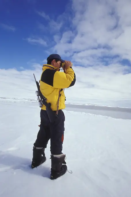 Young Inuit hunter scans horizon at ice flow edge near village of Kimmirut, Baffin Island, Nunavut, Canada