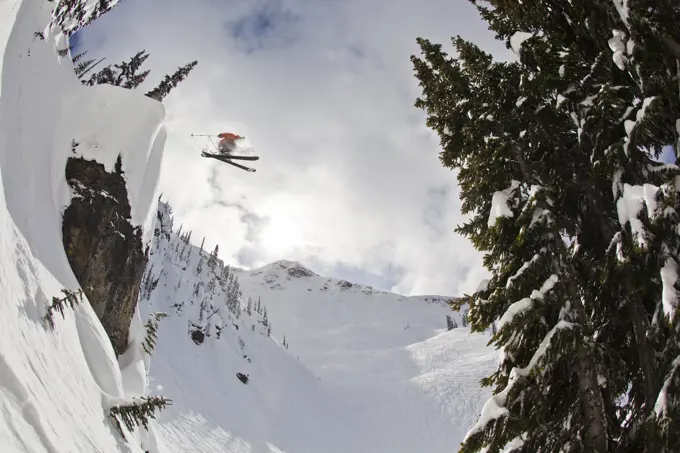 A male freeskier drops a huge cliff at Revelstoke Mtn Resort, BC