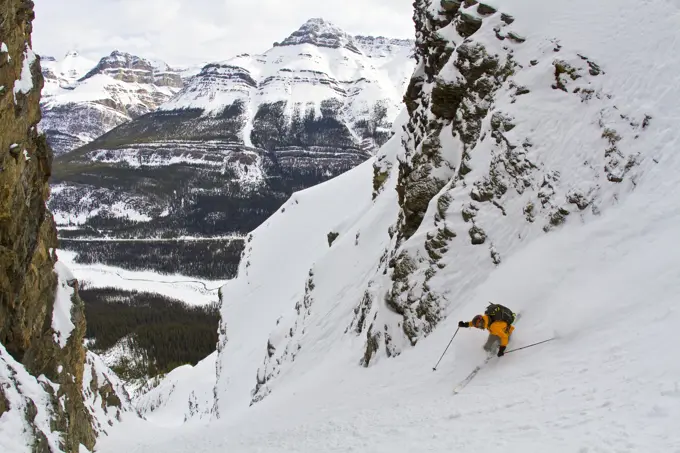 A male backcountry skier on tele skis drops into a steep couloir along the Icefields Parkway, Banff National Park, AB