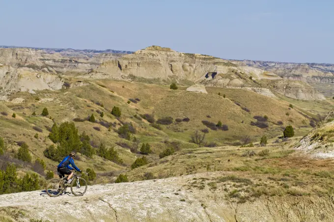 A middle aged man mountain bikes the single track of the Maah Daah Hey Trail, North Dakota