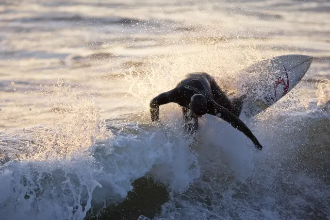 A surfer ripping through the crest of a wave in Rosie Bay, Tofino, Vancouver Island, British Columbia, Canada