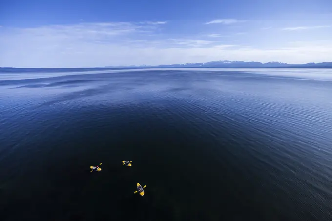 Kayakers skirt along the shoreline, looking south towards Vancouver Island, near Helliwell Bluffs on Hornby Island. Hornby Island, Northern Gulf Islan...