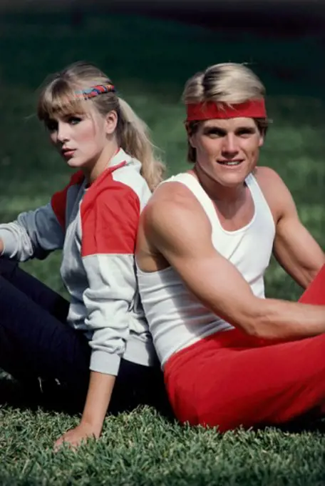 Portrait of a young couple sitting back to back in a park