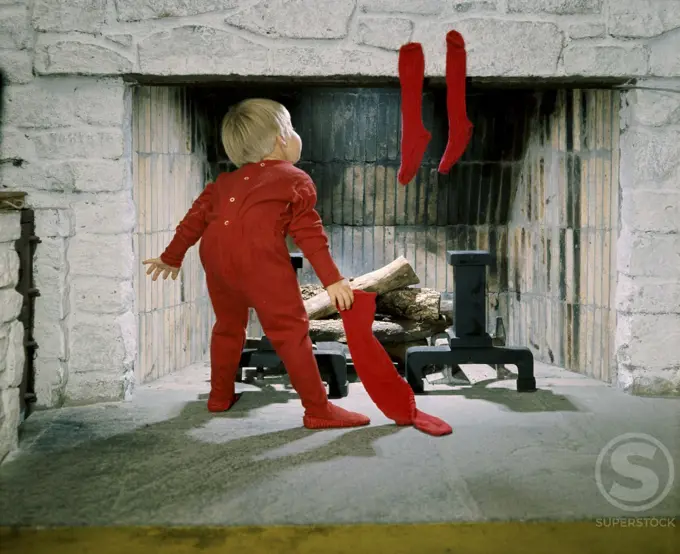 Rear view of a boy holding stockings near a fireplace