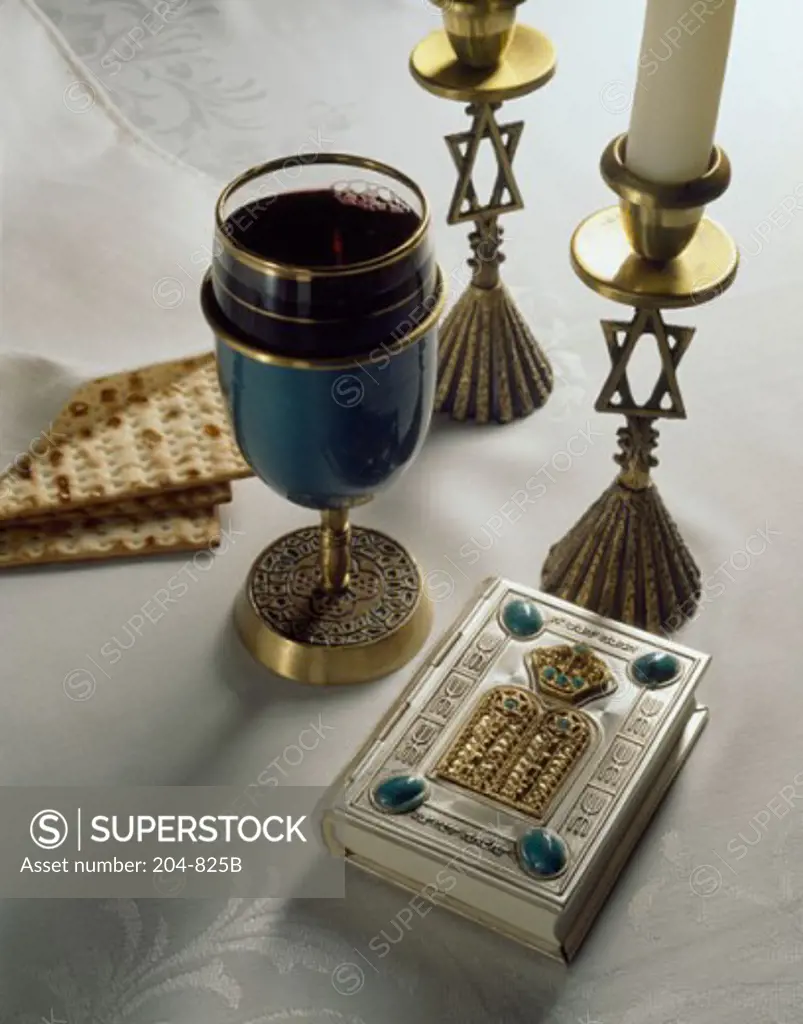 Close-up of two candlestick holders with a glass and two matzo crackers