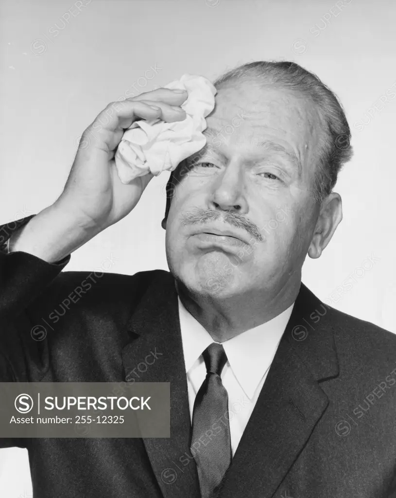 Portrait of a businessman wiping sweat from his forehead