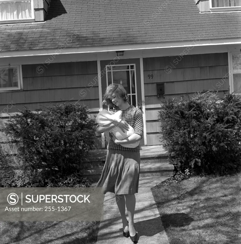 Mother carrying baby outside house