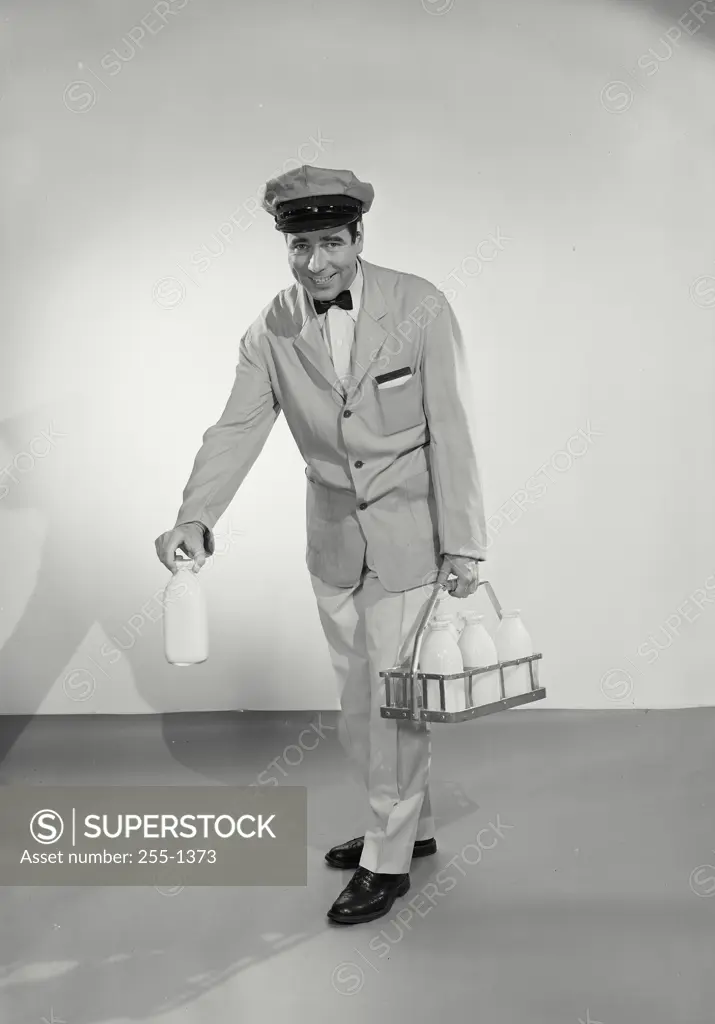 Milkman in uniform carrying case of milk bottles