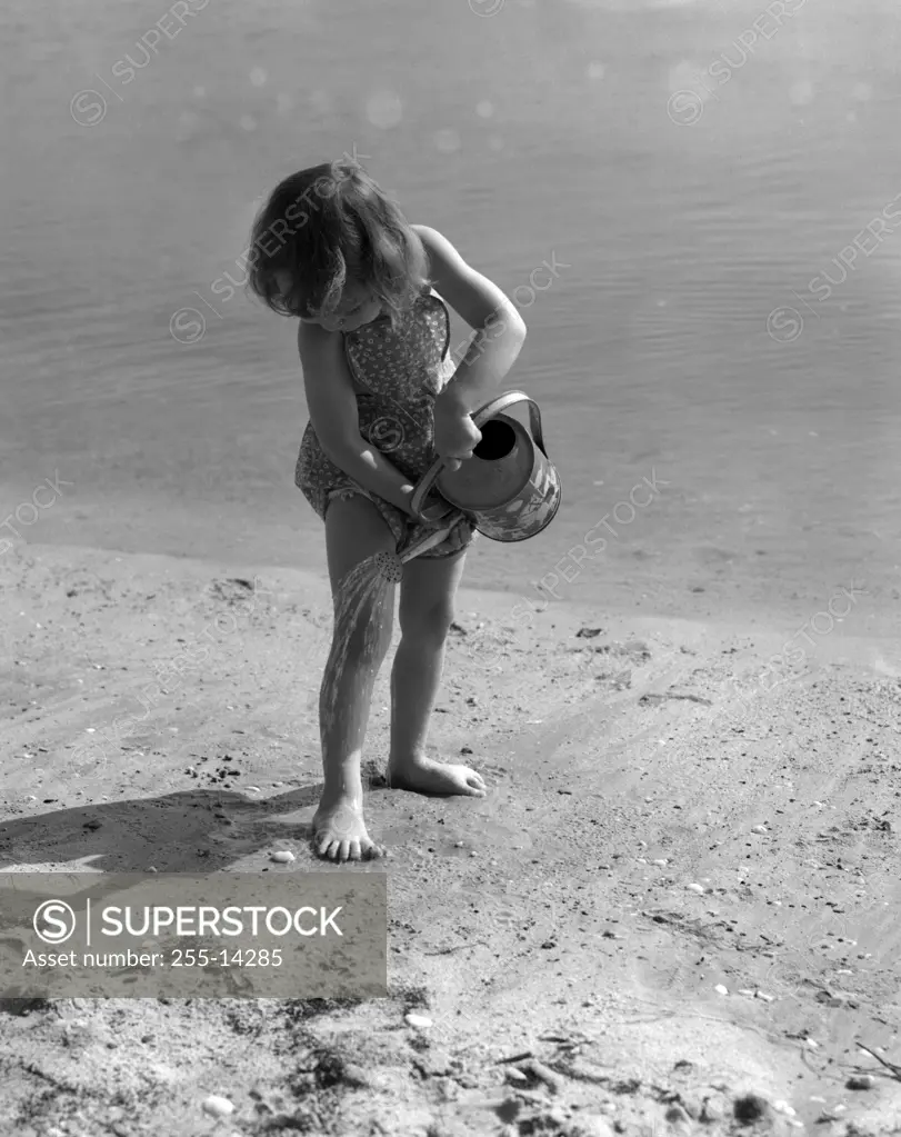 Girl playing on beach with watering can