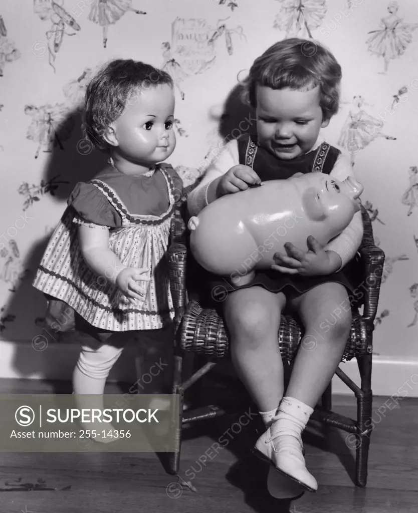 Little girl with piggy bank and doll