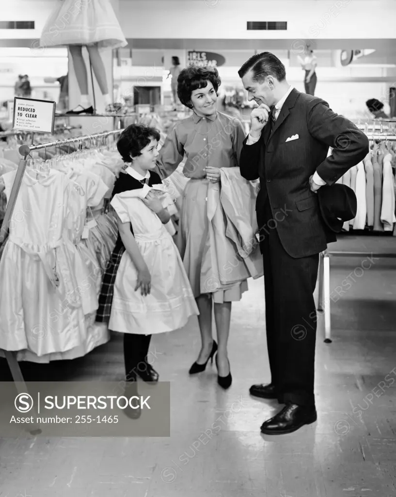 Girl selecting a dress in a clothing store with her parents