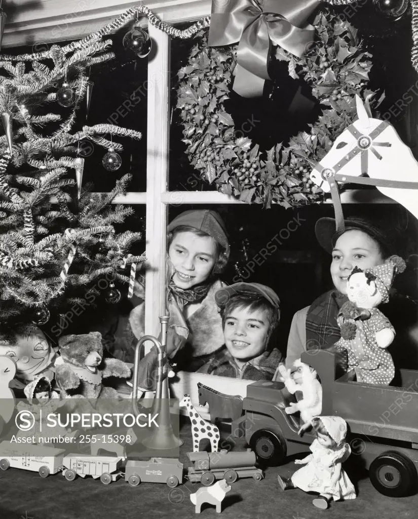 Two boys and their sister looking at toys in the display window of a toy store