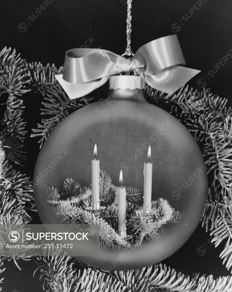 Close-up of burning candles superimposed on a Christmas ornament