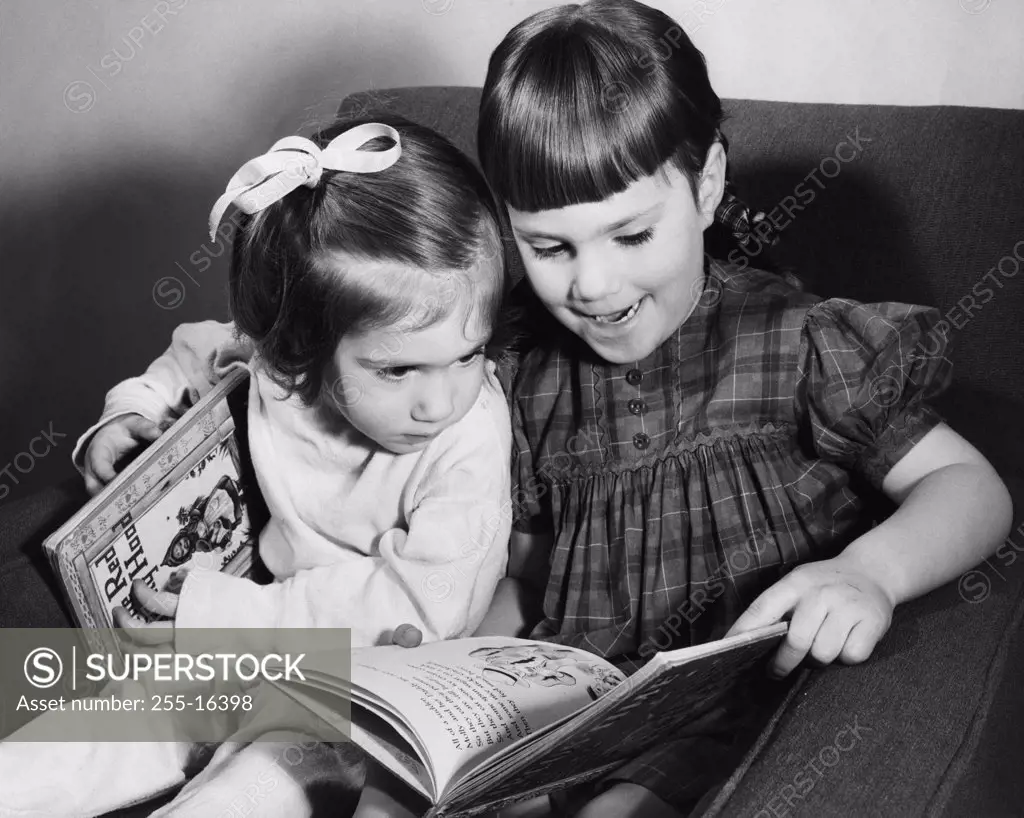 Older sister explaining picture book to younger sister