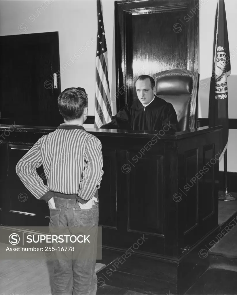 Teenage boy standing in front of a judge in a courtroom