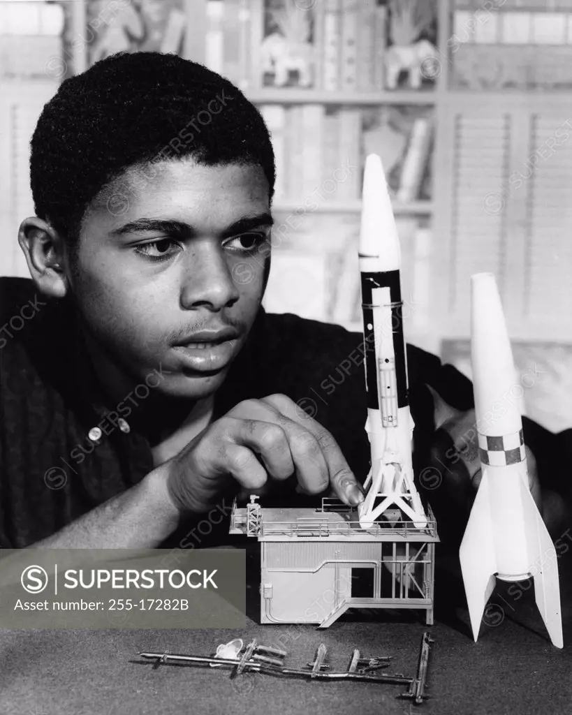 Teenage boy assembling plastic rocket model