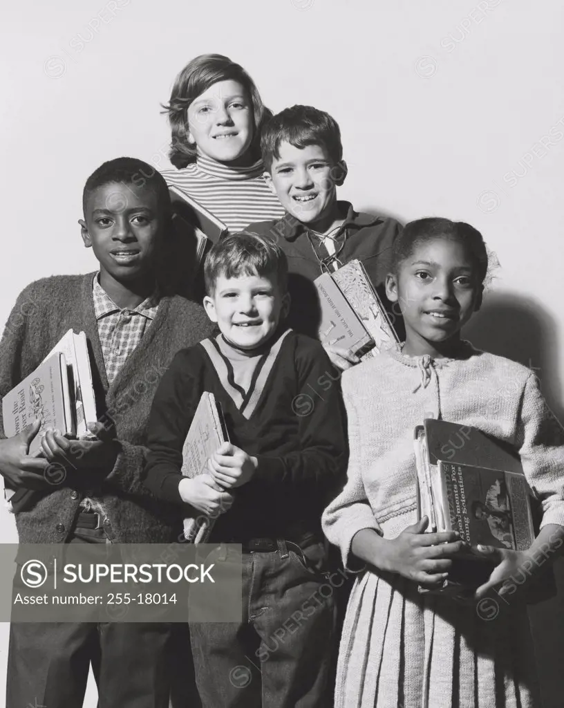 Schoolboys and schoolgirls holding books and smiling