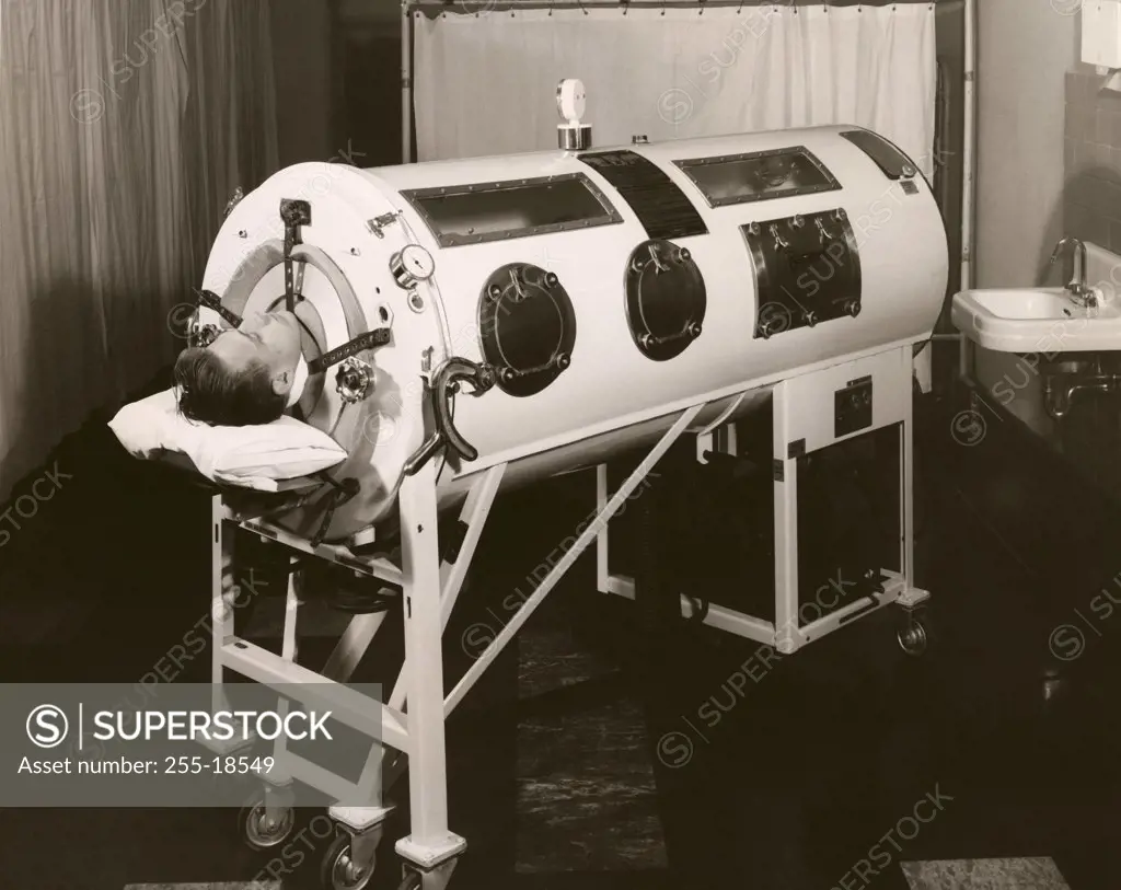 Mid adult man lying in an iron lung