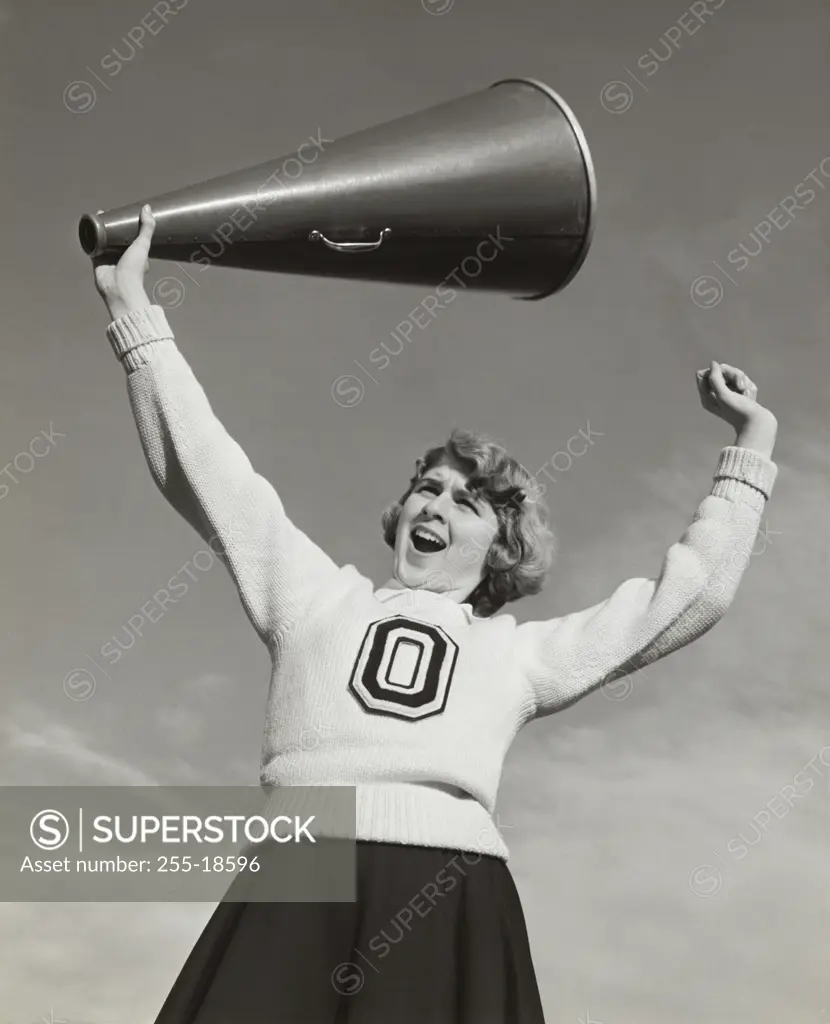 Low angle view of a female cheerleader holding a megaphone and shouting