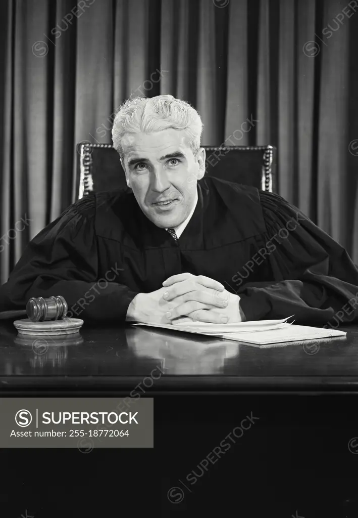 Vintage photograph. Male judge smiling sitting at desk. Model released.