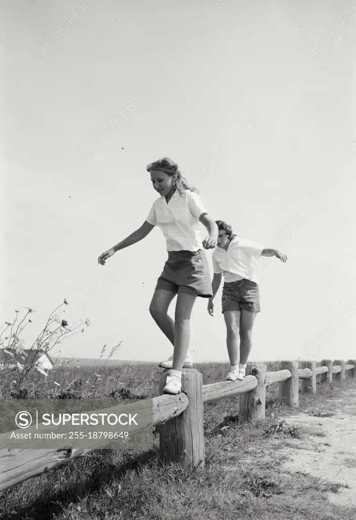 Vintage photograph. Sailing, Long Island Girls walking on low fence posts