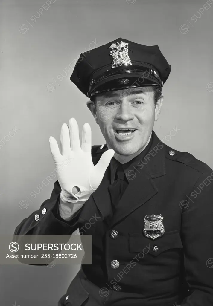 Vintage photograph. Policeman holding up gloved hand smiling with mouth open